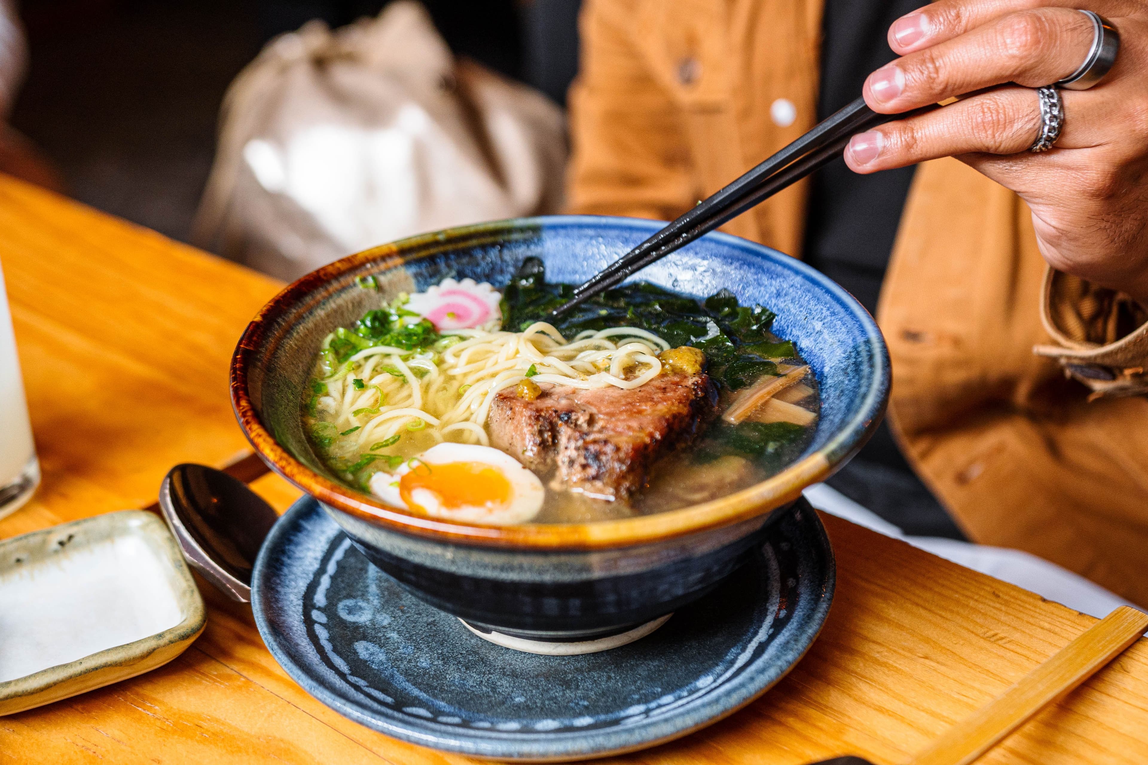 Lifting noodles from a bowl of ramen with chopsticks