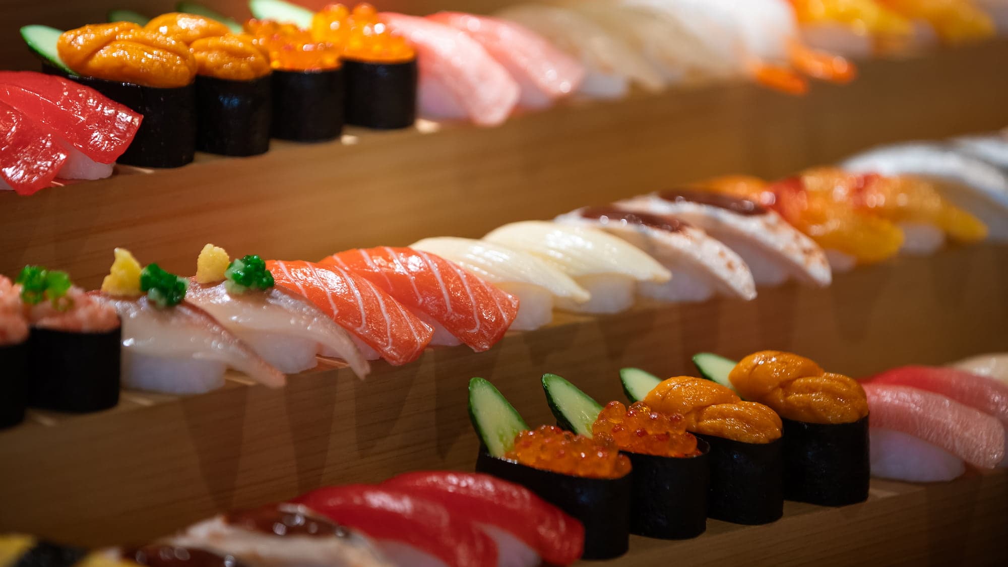Assorted nigiri and gunkan sushi arranged on wooden tiers